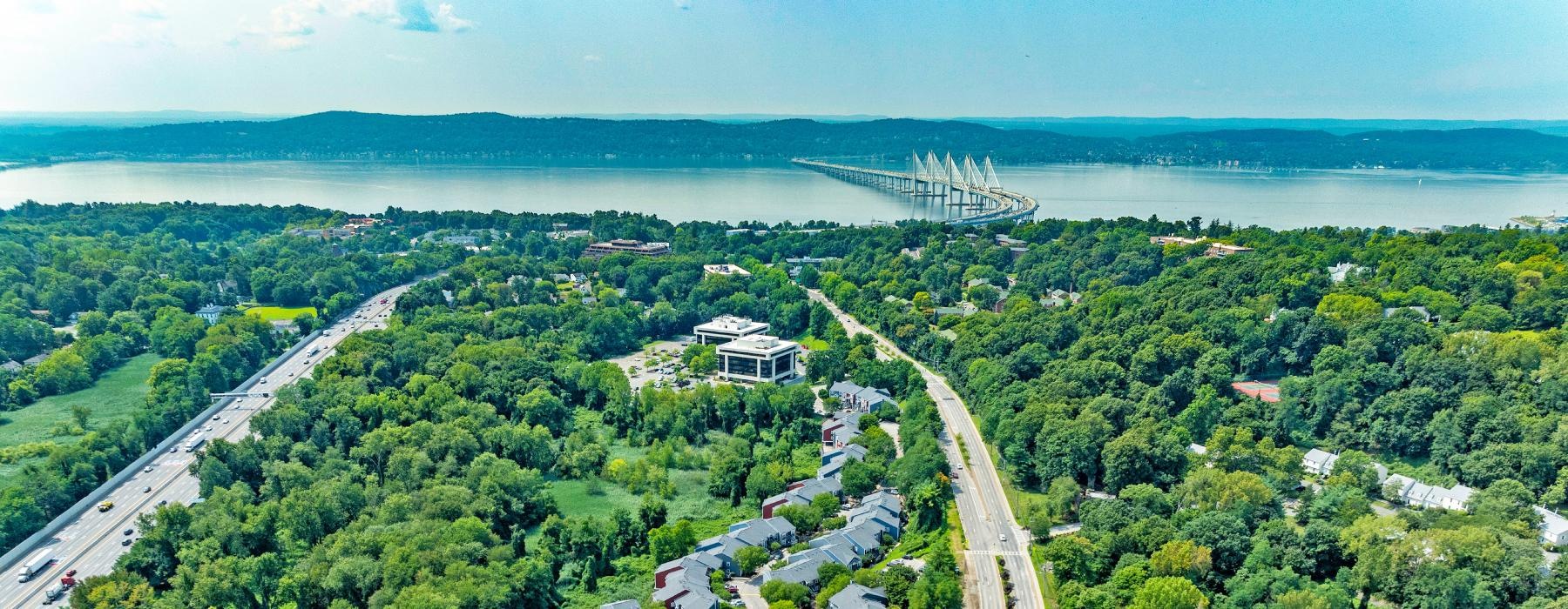 a road with trees and buildings by a body of water